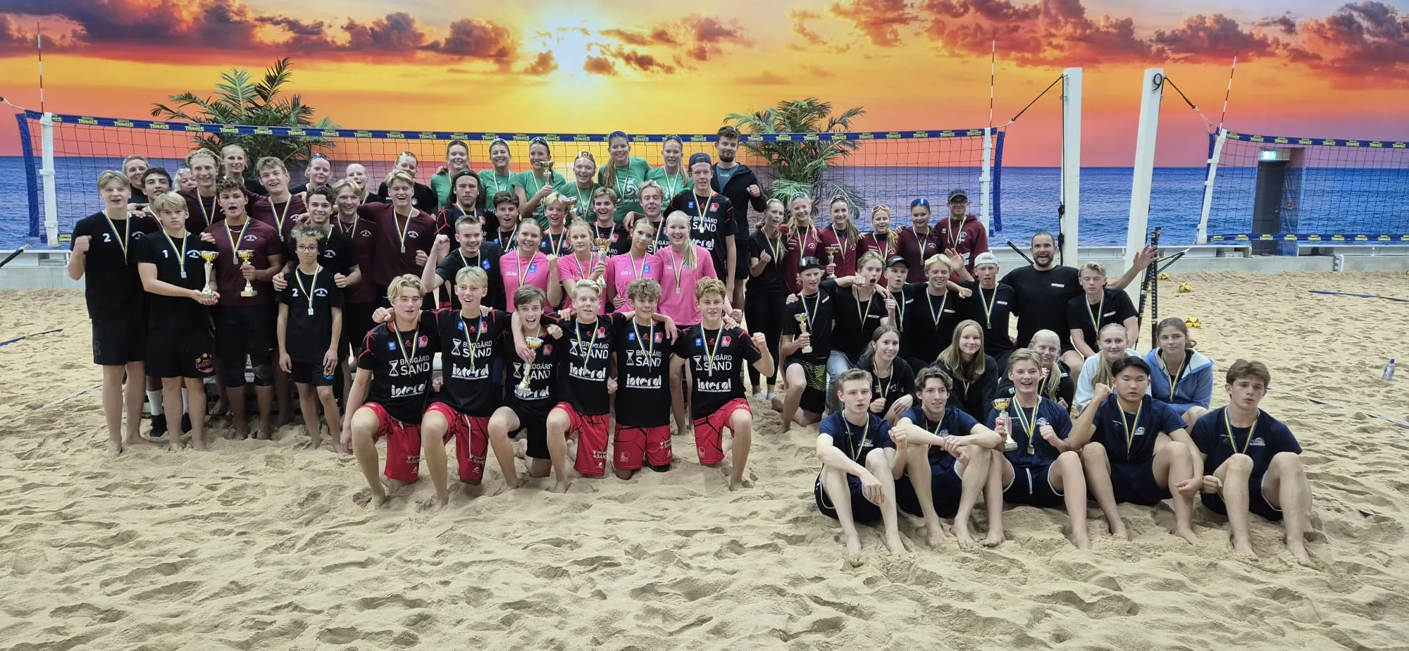 Alla medaljörer i Klubblags-SM för ungdomar 2026 samlade framför solnedgångsväggen på The Beach.