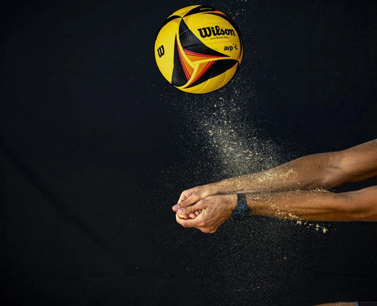 Beachvolleyboll och sand mot svart bakgrund